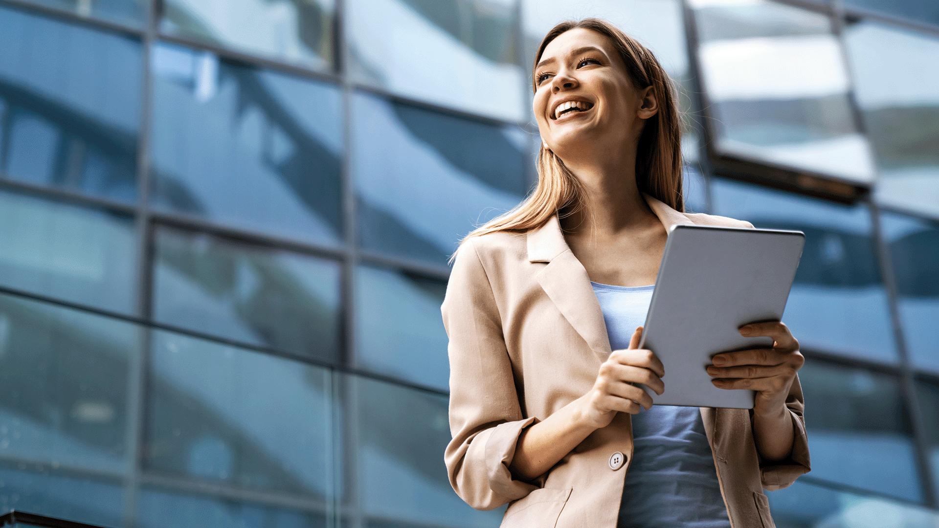 Smiling woman holding paperwork outside an office building